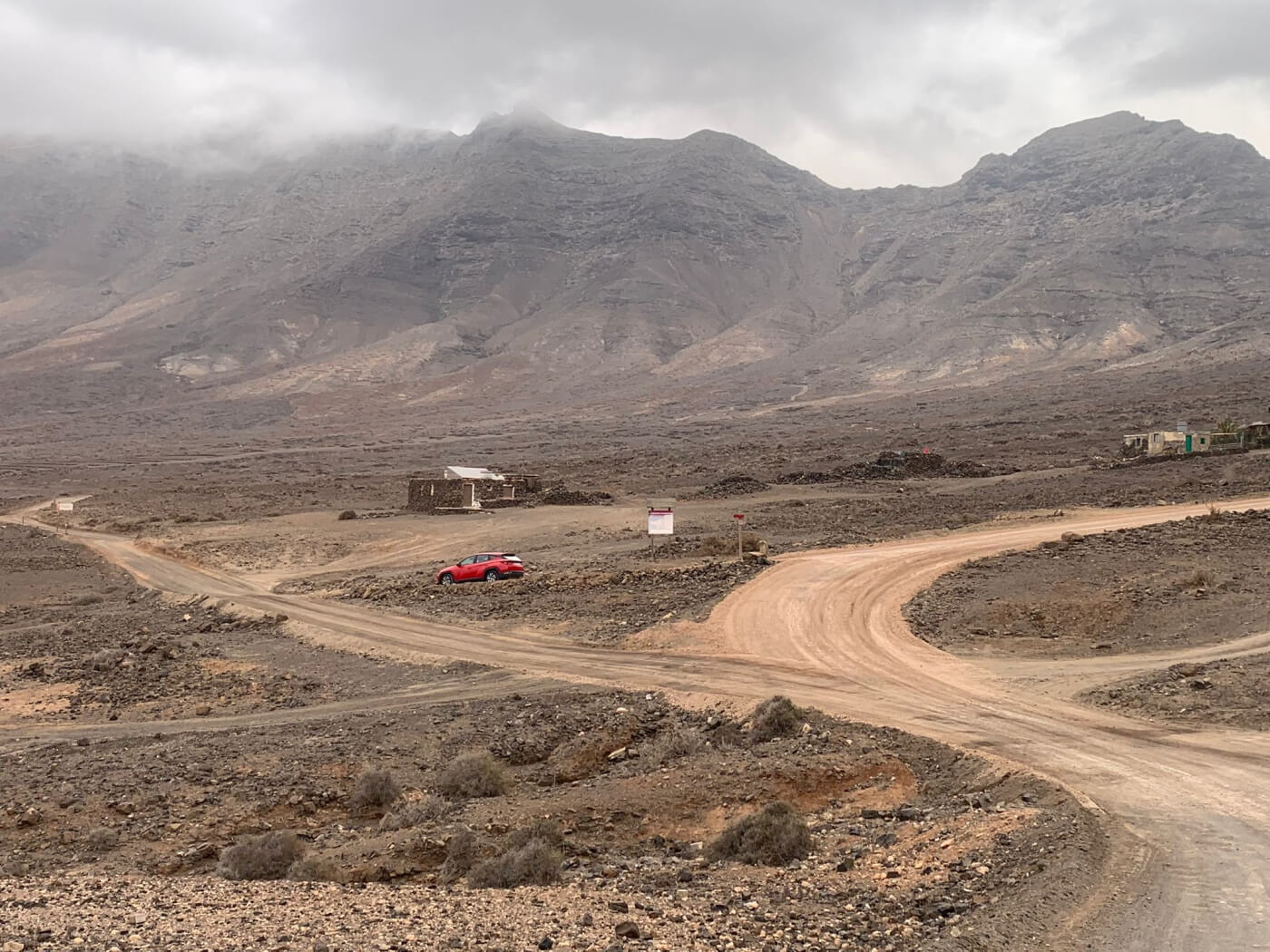 Voiture sur la piste non revêtue au pied des montagnes de Cofete.