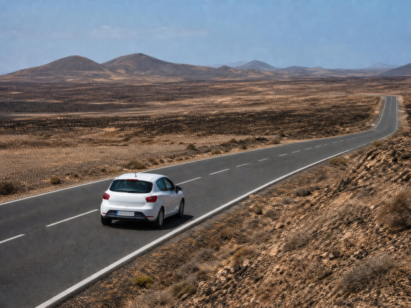Voiture de location sur une route nord-sud à travers le paysage volcanique de Fuerteventura